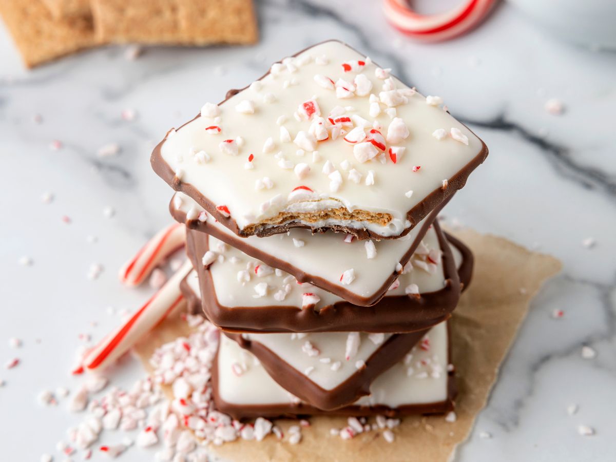 A stack of peppermint bark with candy canes behind it. 