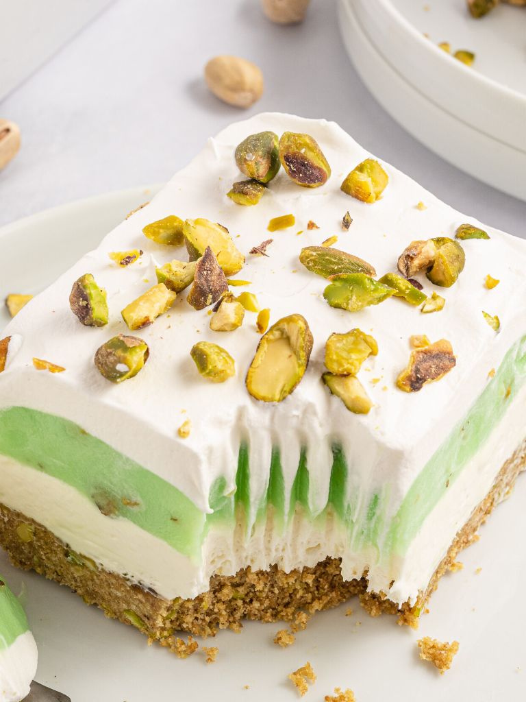 One slice of layered pudding dessert topped with pistachios sitting on a white plate.