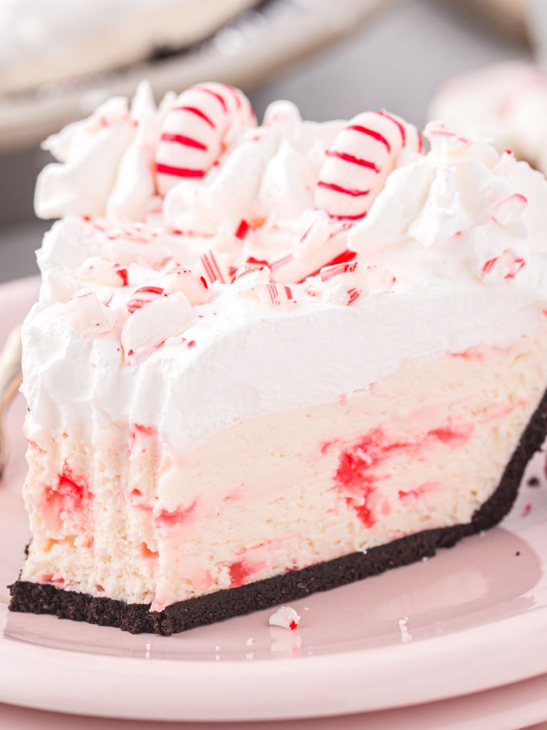 A slice of white chocolate pie with peppermint sitting on a pink plate and with a bite taken out of the front.