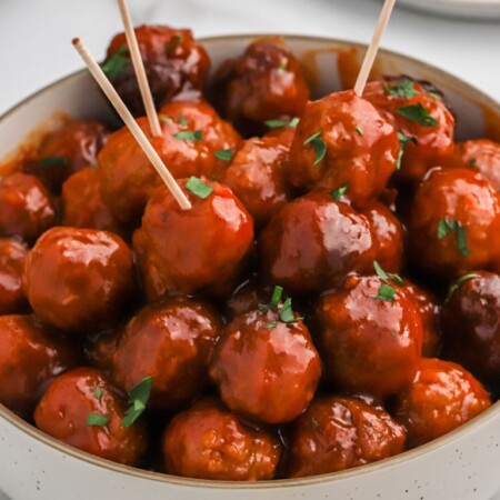 A bowl of meatballs and sauce with toothpicks in the meatballs.