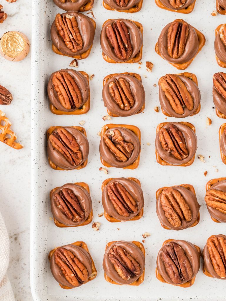 Overhead shot of a cookie sheet with pretzel turtle bites on it. 
