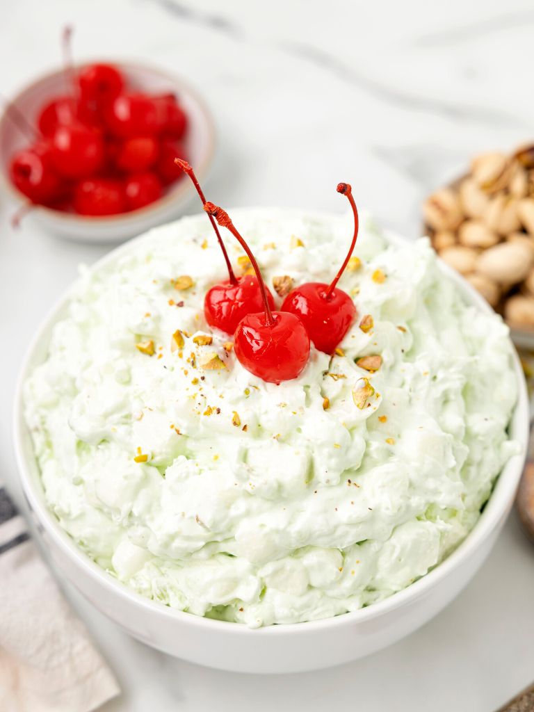 A bowl of salad with cherry on top on a white background. 