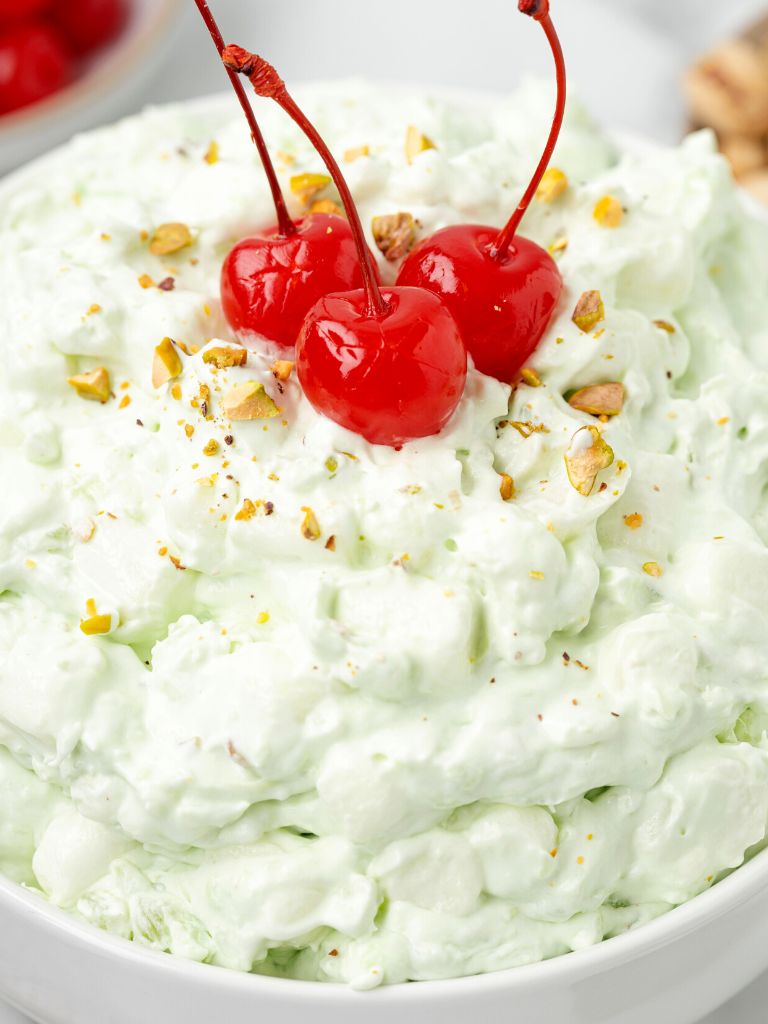 A bowl of fluff salad with cherries on top for garnish. 