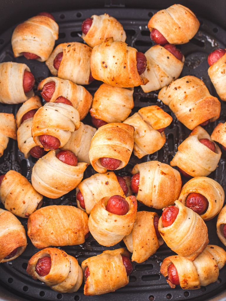 Overhead photo of an air fryer basket filled with cooked pigs in a blankets. 