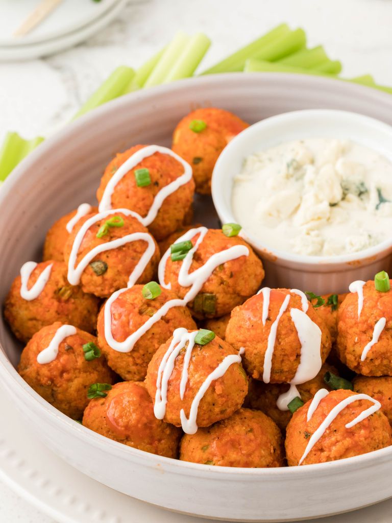 A bowl of appetizer meatballs drizzled with ranch dressing.