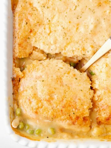 A casserole dish with a serving spoon scooping up a piece of the cobbler inside.