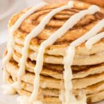 Stack of cinnamon swirl pancakes with a cream cheese glaze dripping over it.