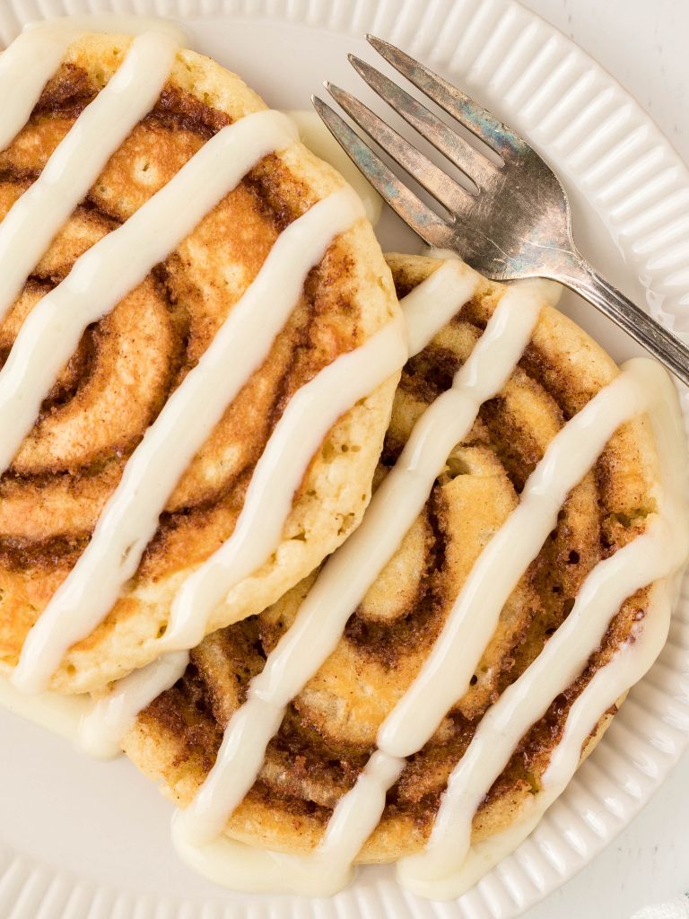 Close up shot of pancakes with cinnamon swirl and cream cheese icing on top. 