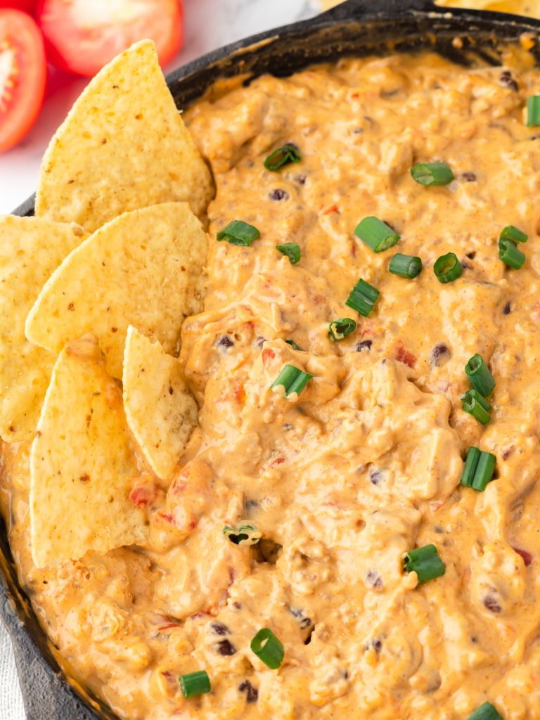 A skillet with cheesy dip inside of it and tortilla chips to the side inside the pan. 