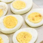 A tray of eggs that have been cooked, sprinkled with salt and pepper.