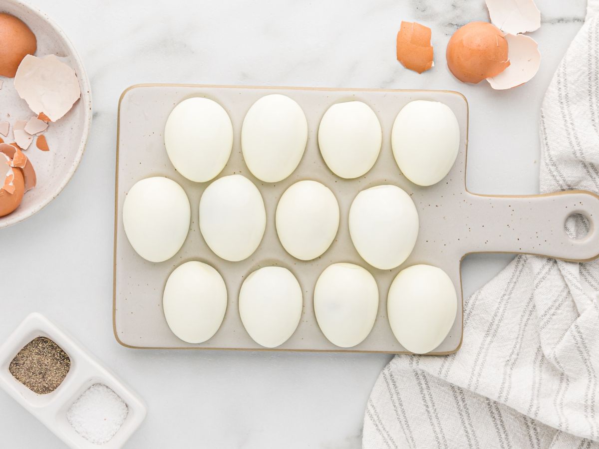 A tray of peeled eggs with the shells nearby to show how easy the shell peels off. 