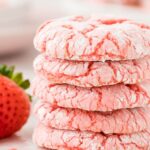 A stack of cookies with a fresh strawberry beside it.