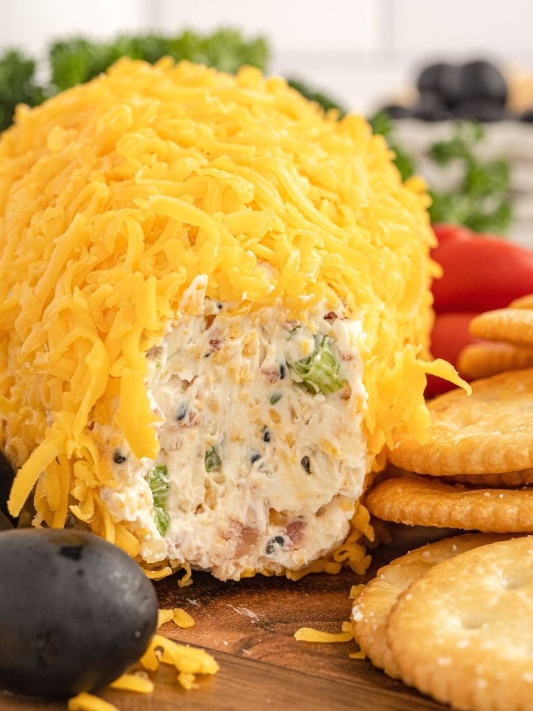 A appetizer with the front eaten out of it to show the inside of the cream cheese ball. 