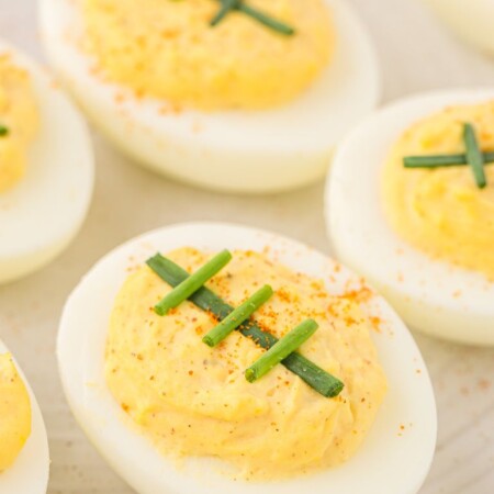 A white plate with eggs that are hard boiled and deviled eggs on it.