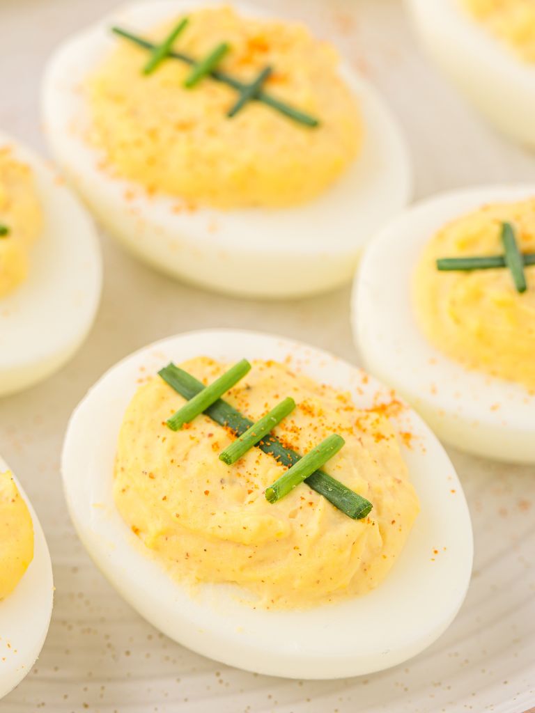 A white plate with eggs that are hard boiled and deviled eggs on it. 