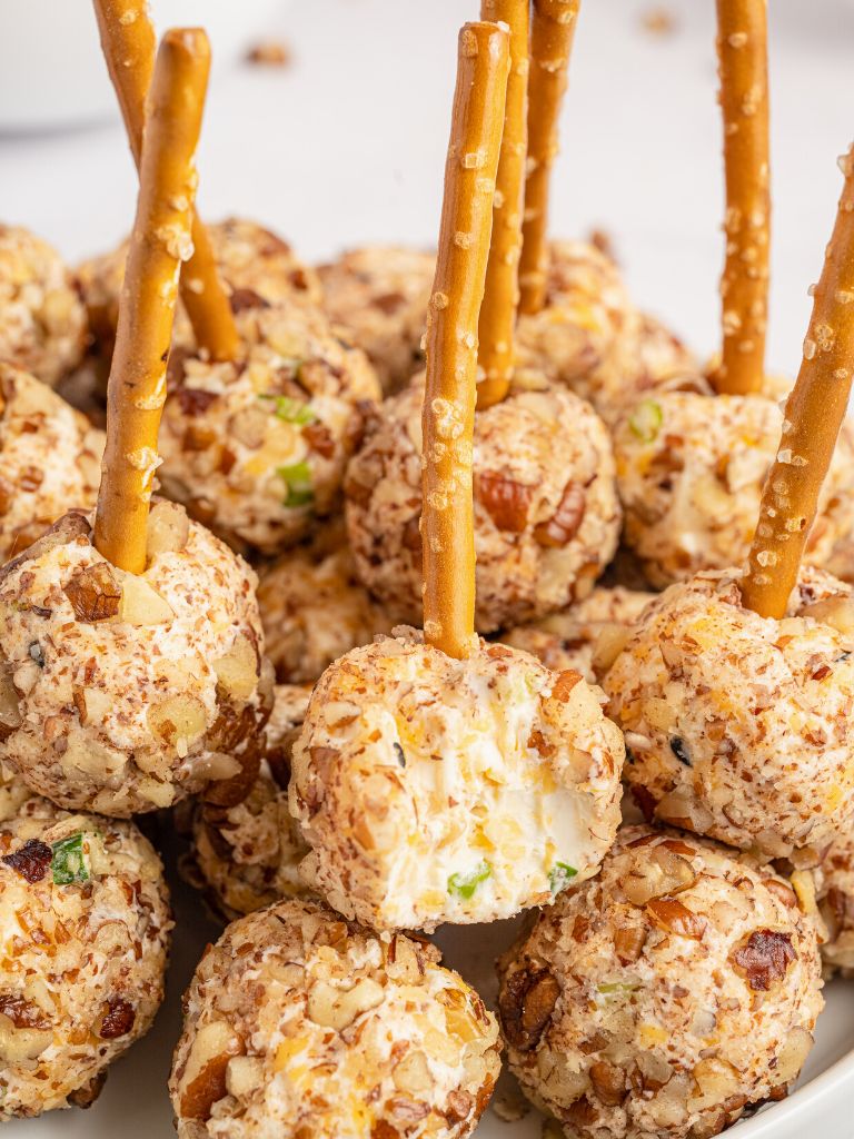 A appetizer on a pretzel stick on a white plate. 