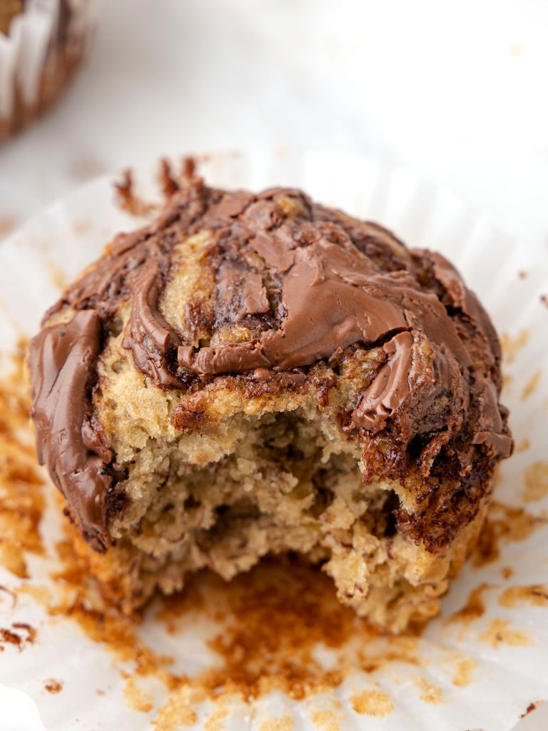 A side view photo of an unwrapped muffin from the paper liner with a bite taken out of it. 