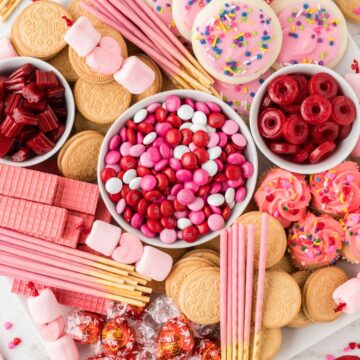 Overhead shot of a dessert board with red and pink candies all over it.