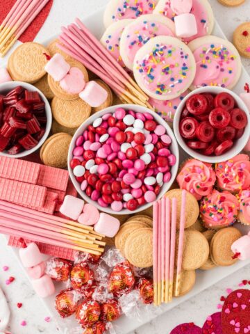 Overhead shot of a dessert board with red and pink candies all over it.