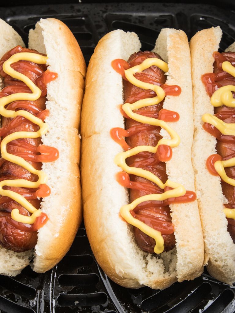 Hot dogs inside buns topped with ketchup and mustard. 