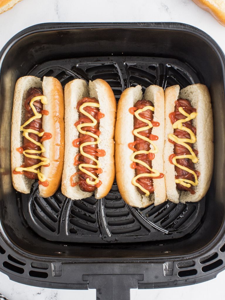Hot dogs inside the air fryer basket that have been cooked. 
