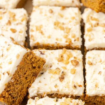 Cut carrot cake bars with walnuts on top. Some tuned on their side to show the inside of the bars.