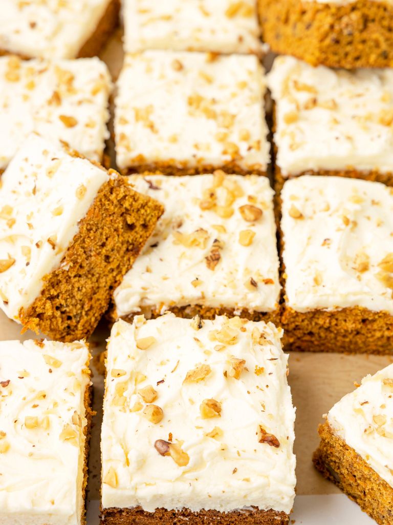 Carrot cake bars with some on their side and laid on a parchment paper background.