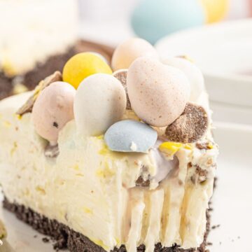 A slice of cheesecake with easter candy, a fork bite taken out of the front of the piece.