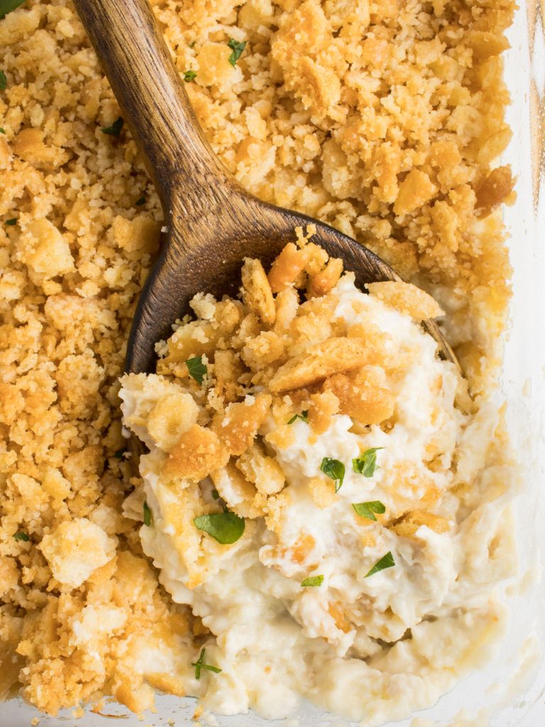 A wooden spoon with a scoop of this creamy casserole sitting on it.