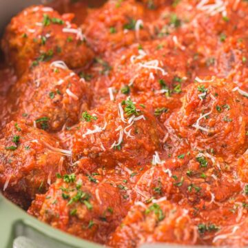 A pan of meatballs with sauce over them and parmesan cheese.