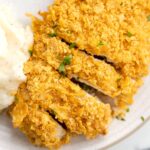 Square photo of chicken coated in cornflake cereal, cut into slices.
