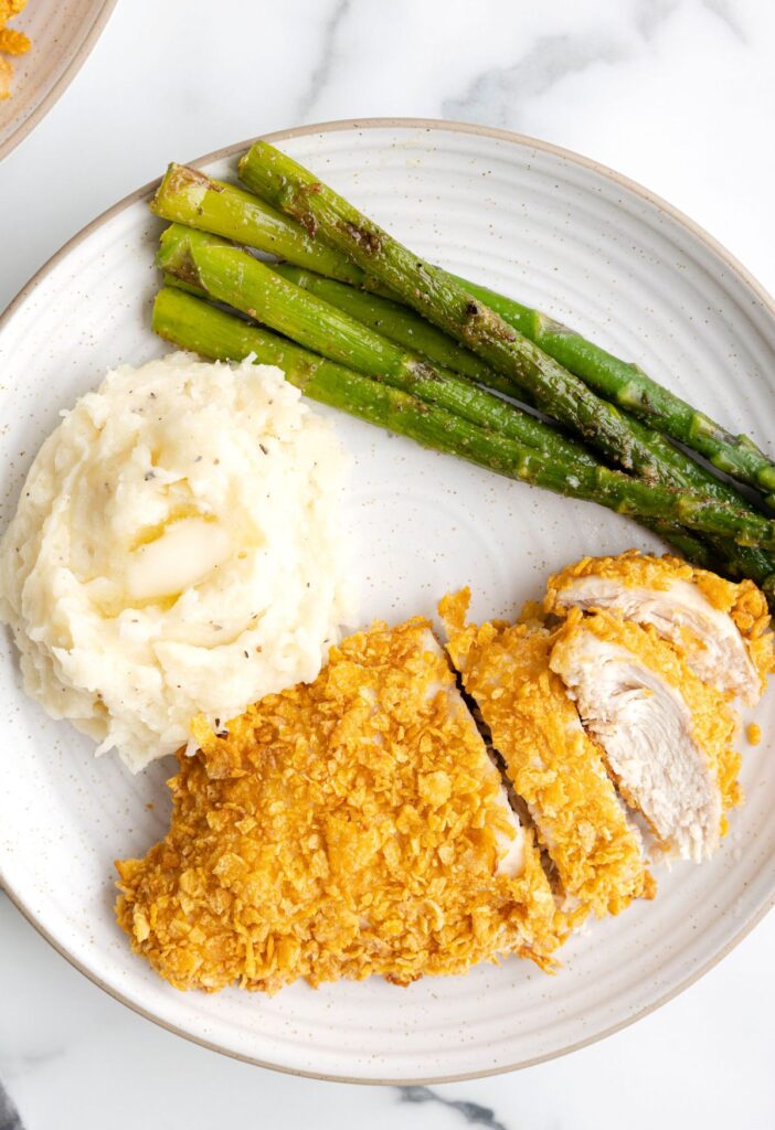 A dinner plate with chicken, asparagus, and mashed potatoes on it. 