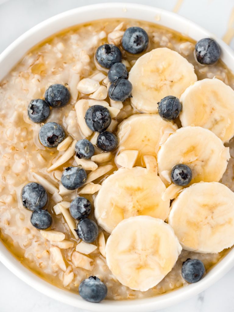A bowl of oats topped with blueberries, almonds, and banana.
