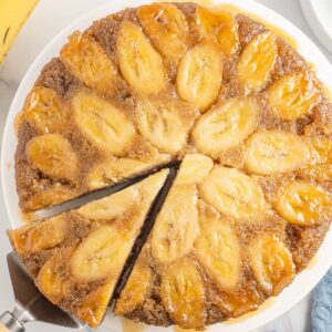 A upside down cake with banana and a slice cut from the cake.