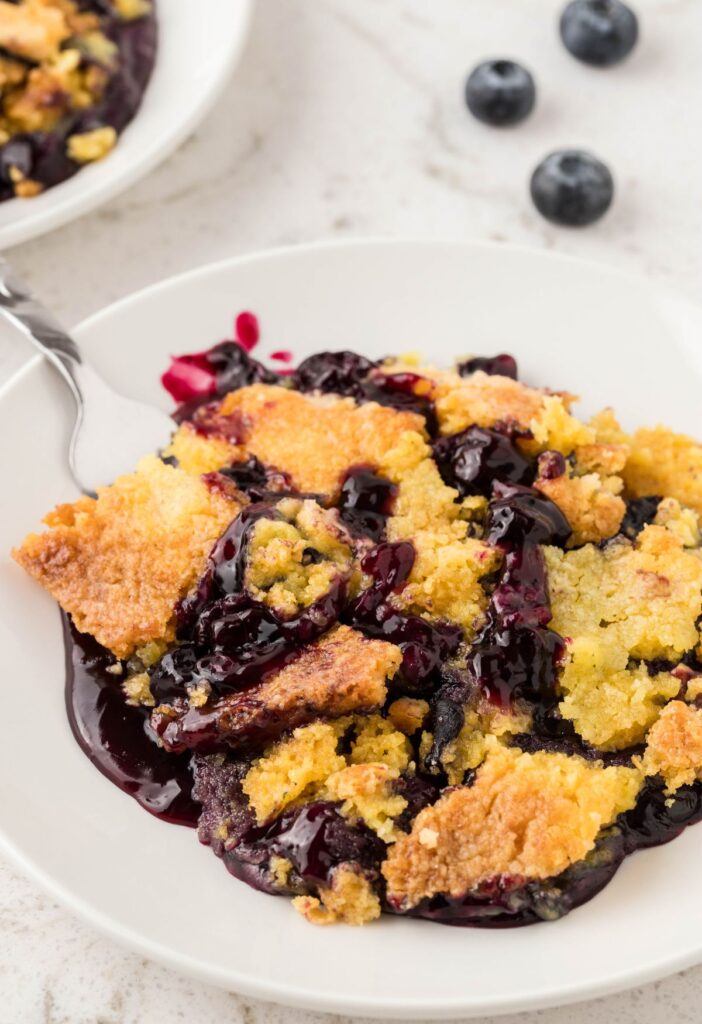 A serving of this dump cake with a spoon by it on a white plate. 