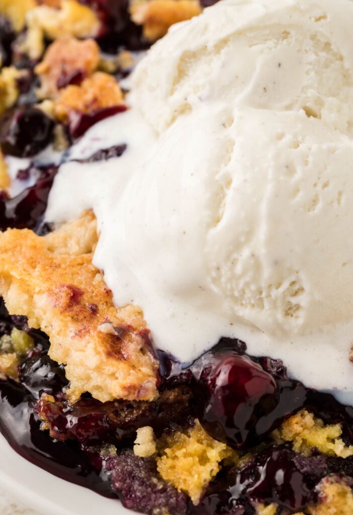A scoop of melted ice cream on top of this serving of blueberry dump cake. 