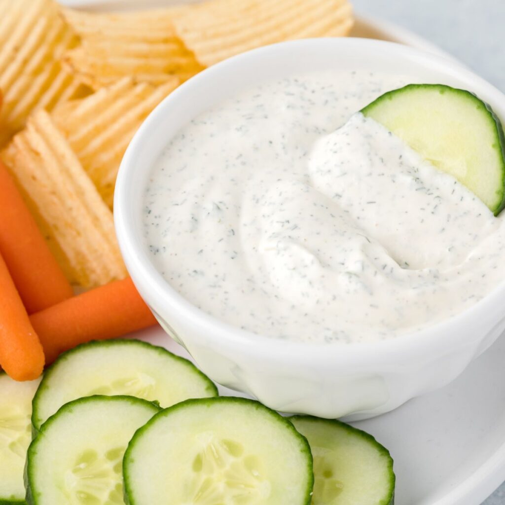 A cucumber inside the bowl of ranch dip
