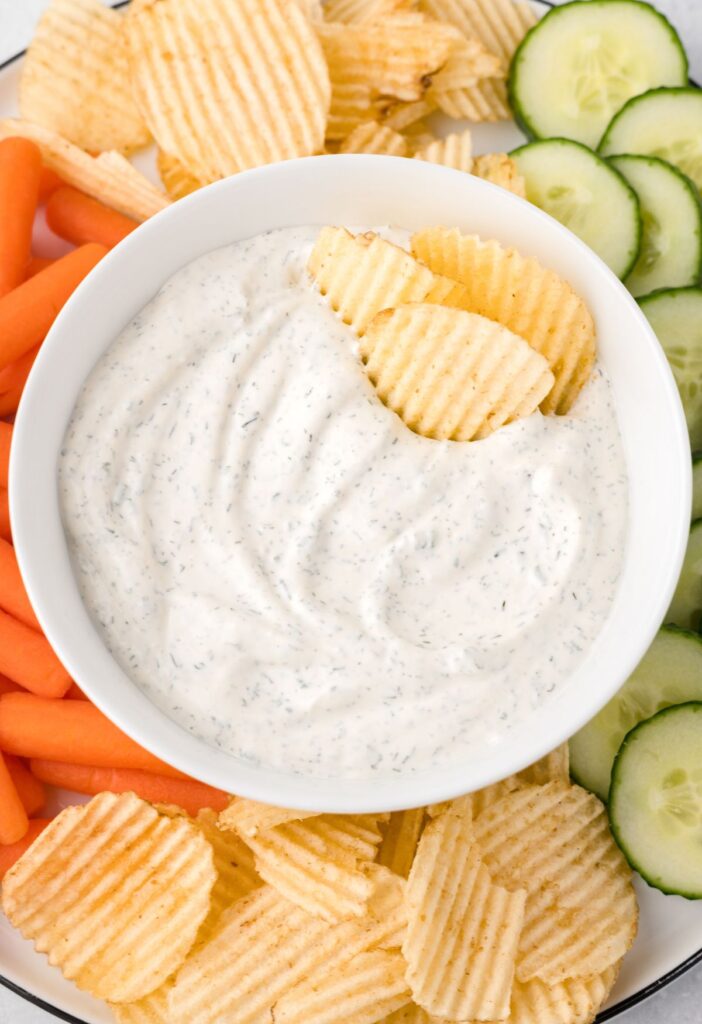 Dip with chips and veggies around it. 