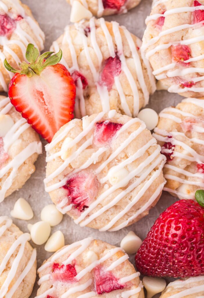 Cookies with a glaze with strawberries next to them. 