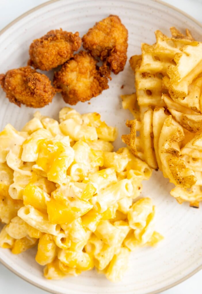 A plate of the Mac and cheese with chicken nuggets and waffle fries from chick-fil-a. 