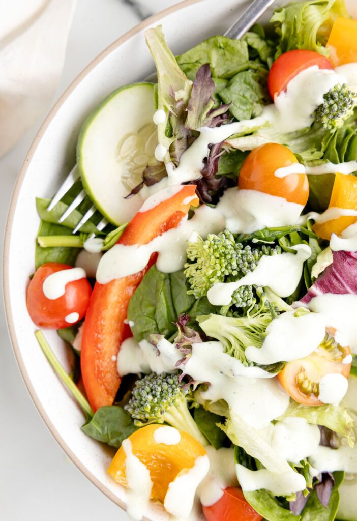 Green salad with ranch dressing over top it. 