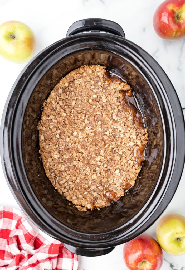 A crockpot of cooked apples dessert with an oatmeal topping that is crispy. 