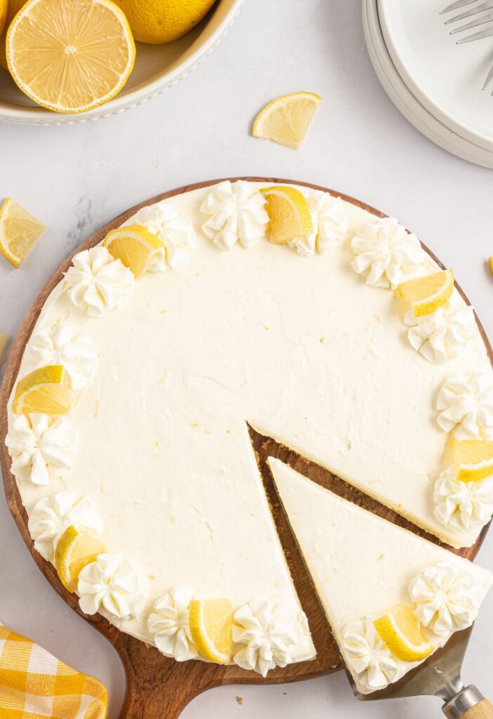 Overhead shot of a cheesecake being serving with lemons in the background. 