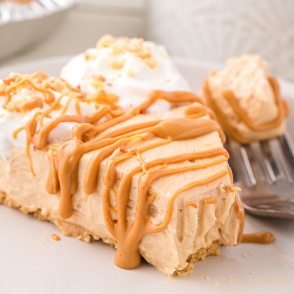 A slice of pie drizzled with peanut butter with a fork next to it. 