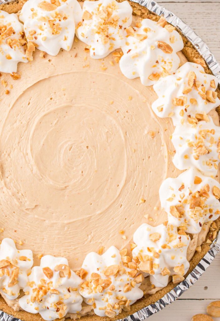 Overhead picture of a pie garnished with cool whip and peanuts. 