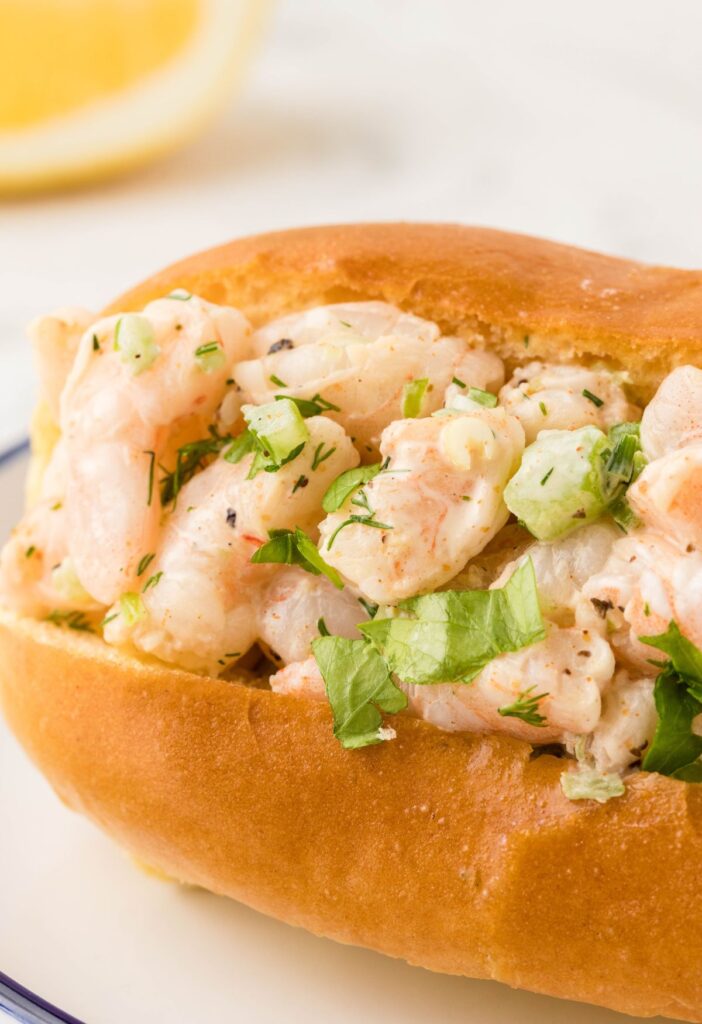 Side view of a serving plate of a brioche bun with shrimp inside. 