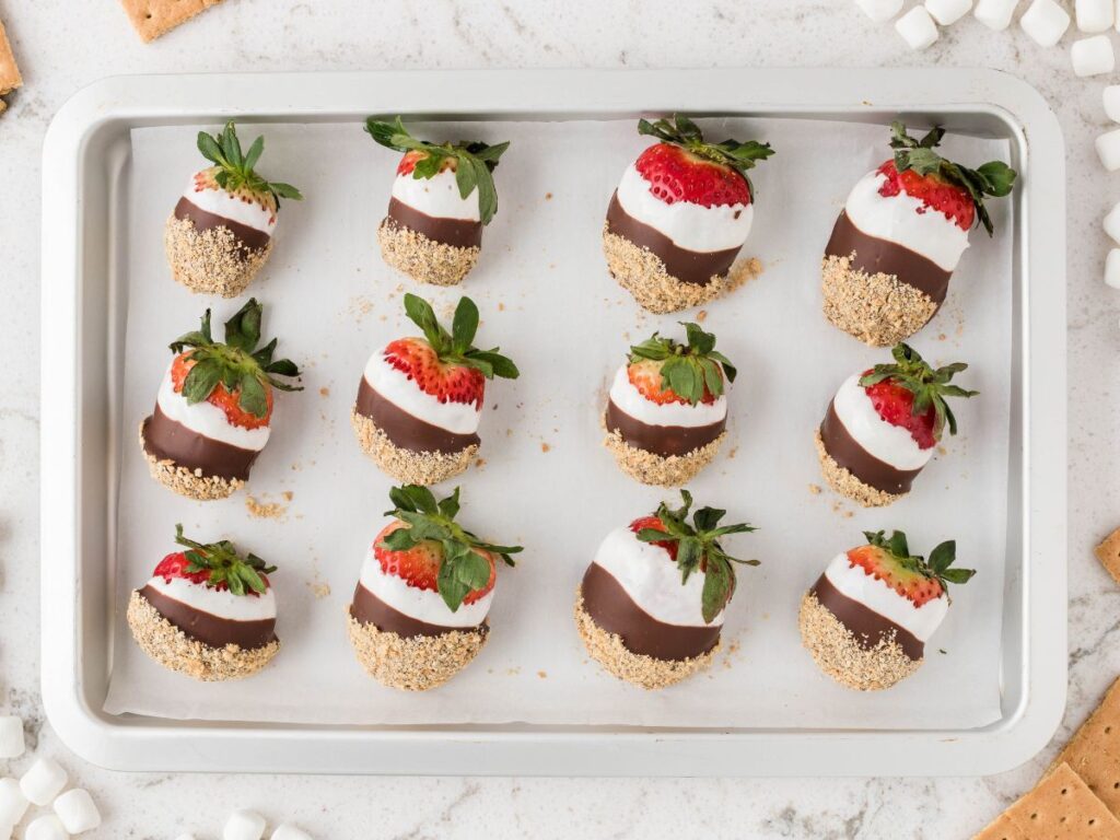Photos showing how to make this dipped strawberry recipe with layers of s'mores.
