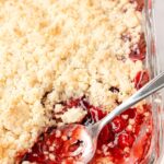 A pan of cobbler with a spoon taking a scoop out of it.