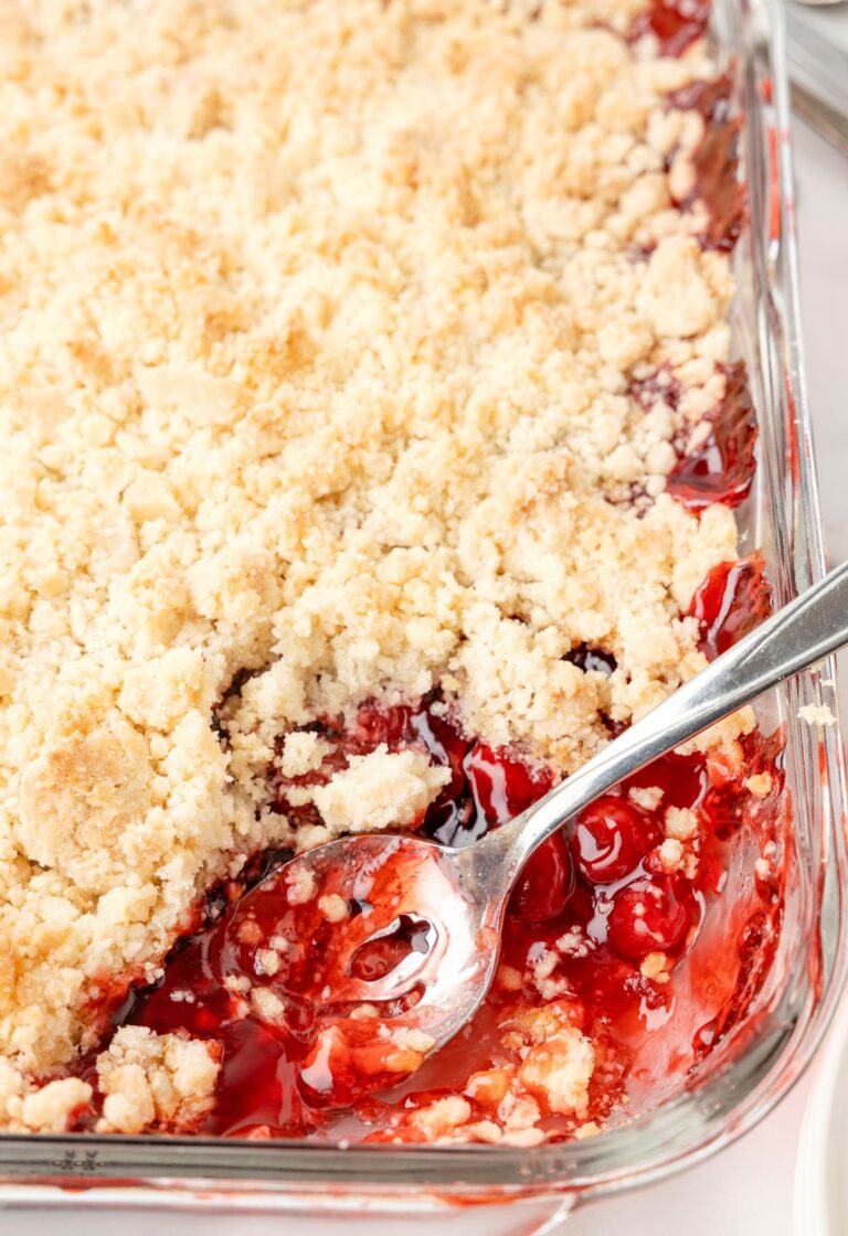 A pan of cobbler with a spoon taking a scoop out of it.