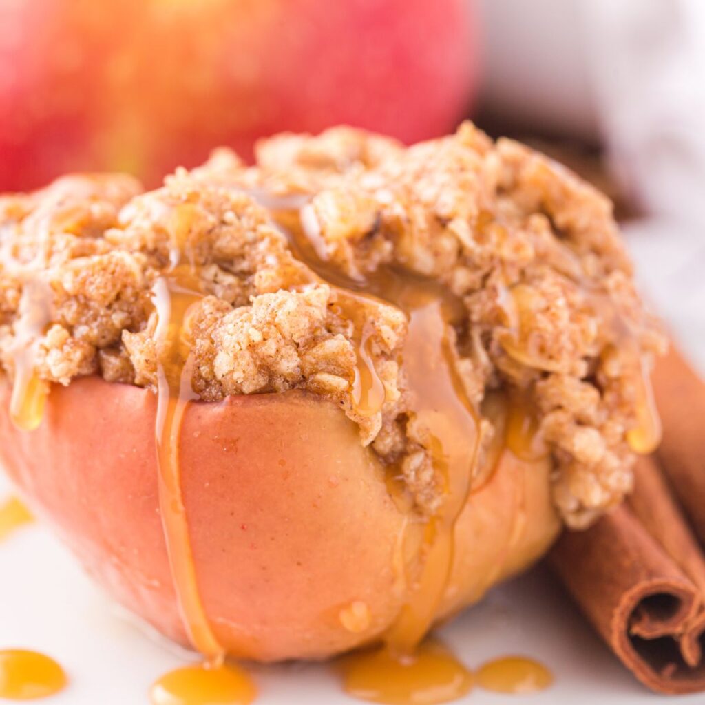 An apple topped with crumble and has caramel sauce running down it. 